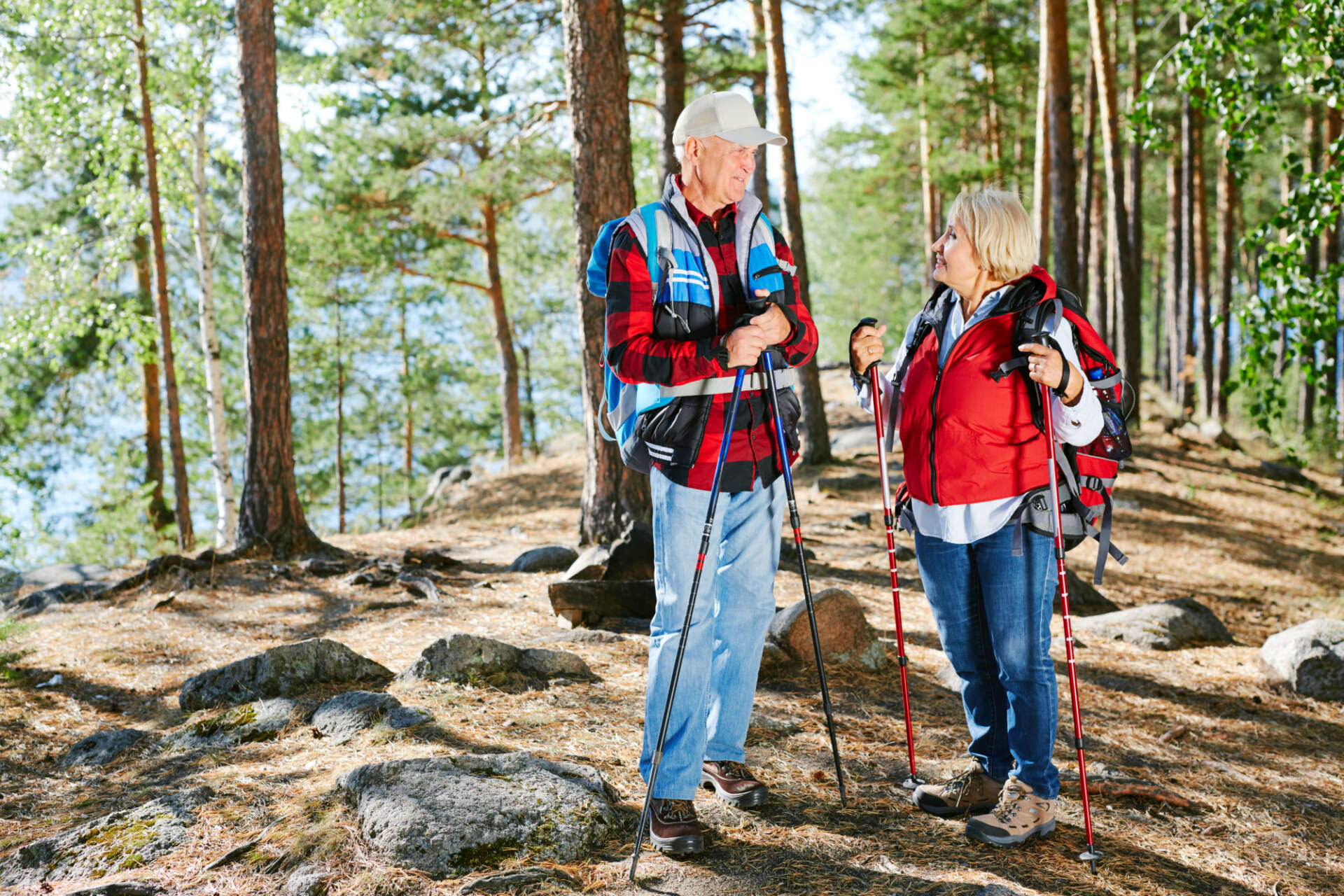 Ein Ehepaar steht im Wald, mit Wanderstöcken in den Händen.