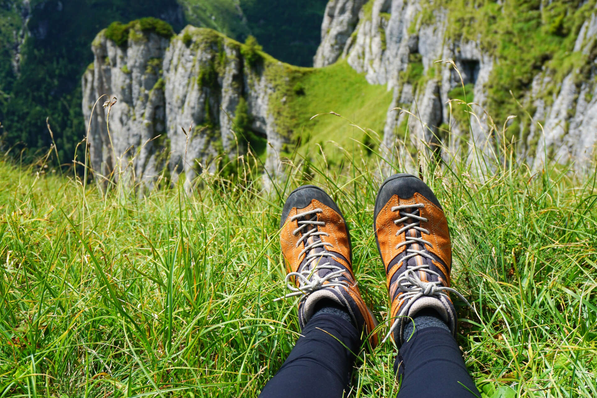 Eine Person sitzt auf einem Berg und genießt den Ausblick, man sieht nur ihre Wanderschuhe.