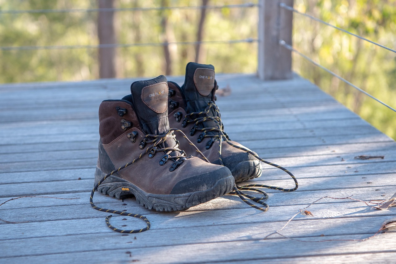 Ein Paar braune Wanderschuhe mit offenen Schnürsenkeln steht auf einer Holzplattform im Freien.