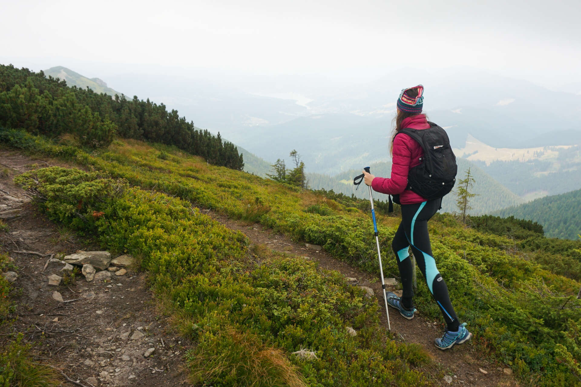 Eine Frau beim Bergsteigen, dazu benutzt sie Wanderstöcke.