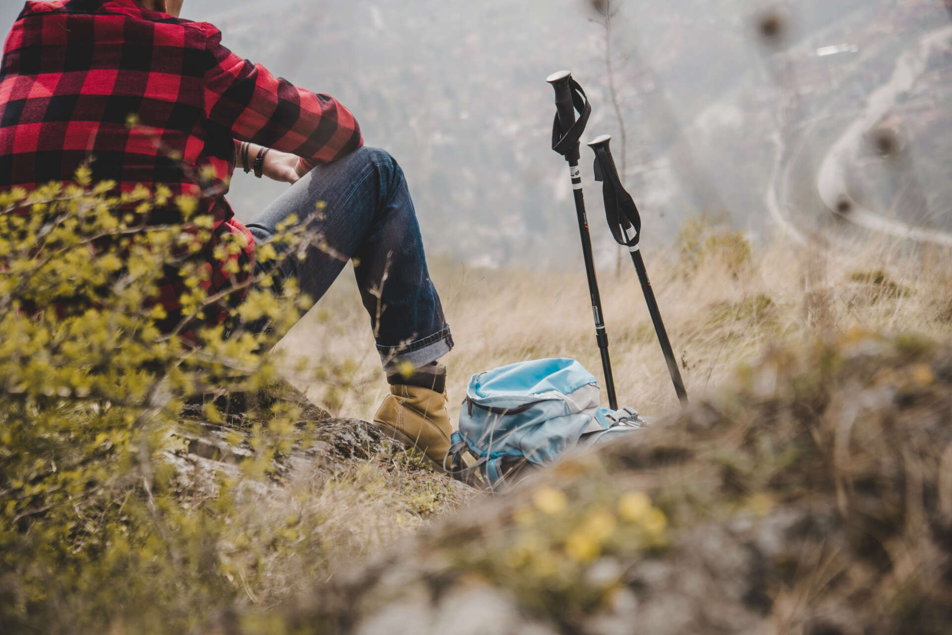 Pause beim Bergsteigen mit Wanderstöcken: Ein Mann macht Rast und genießt den Ausblick.