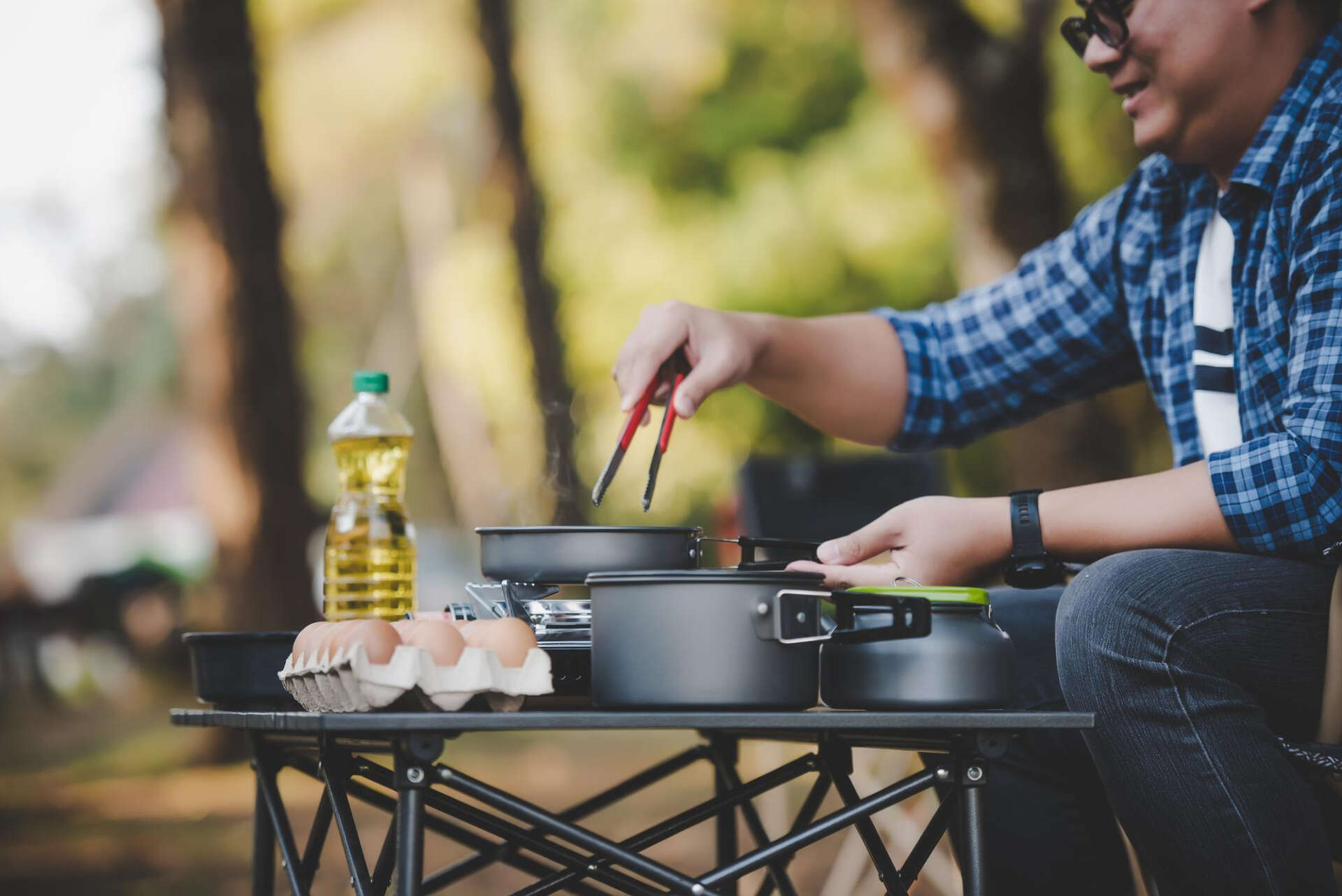 Ein Mann kocht draußen mit Campingzubehör: Auch draußen, etwa beim Wandern, ist das möglich.
