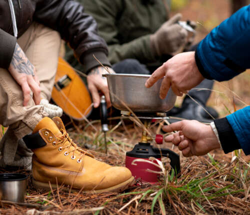 Kochen beim Wandern: Wanderer verwenden einen Gaskocher, um Essen zuzubereiten.