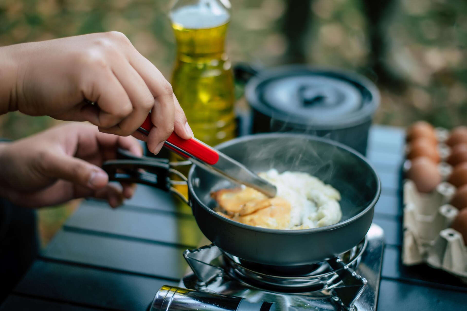 Beim Wandern kochen: Eine Person bereitet sich mit Gaskocher und Topf ein Gericht zu.