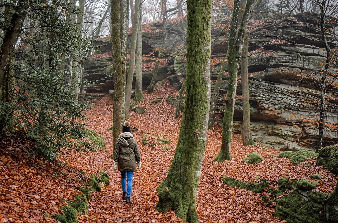 Welcher Puls ist beim Gehen normal? Das Bild zeigt eine Frau, die im Wald spaziert.