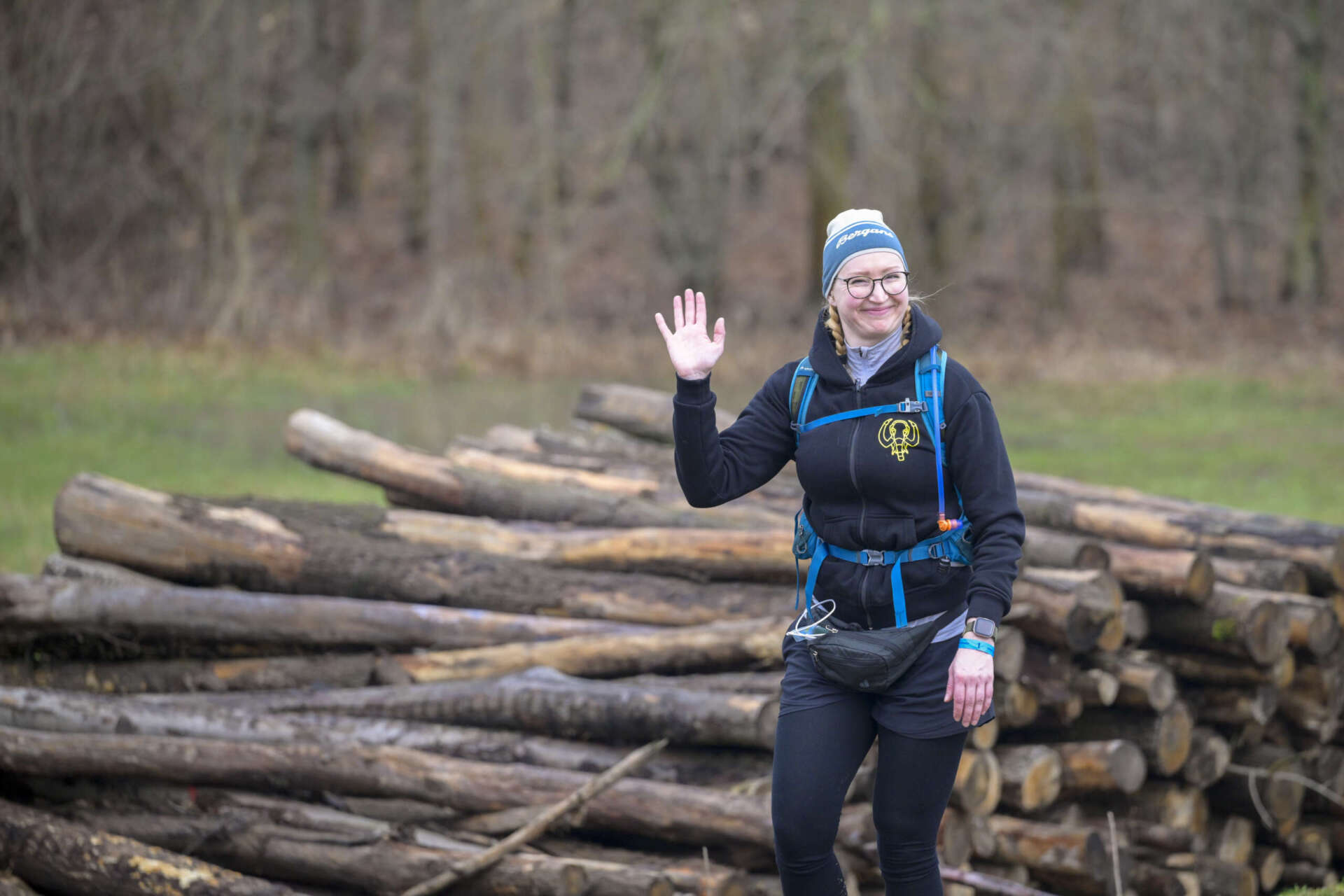 Wandern beim Mammutmarsch: Eine junge Frau winkt lächelnd in die Kamera.