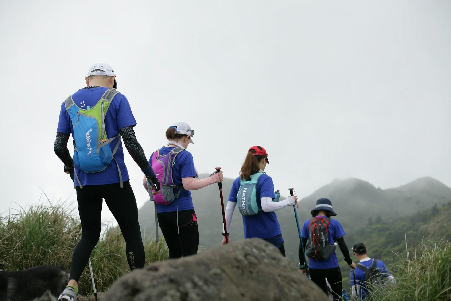 Gruppe beim Nordic Walking auf einem bergigen Trail in unebenem Gelände