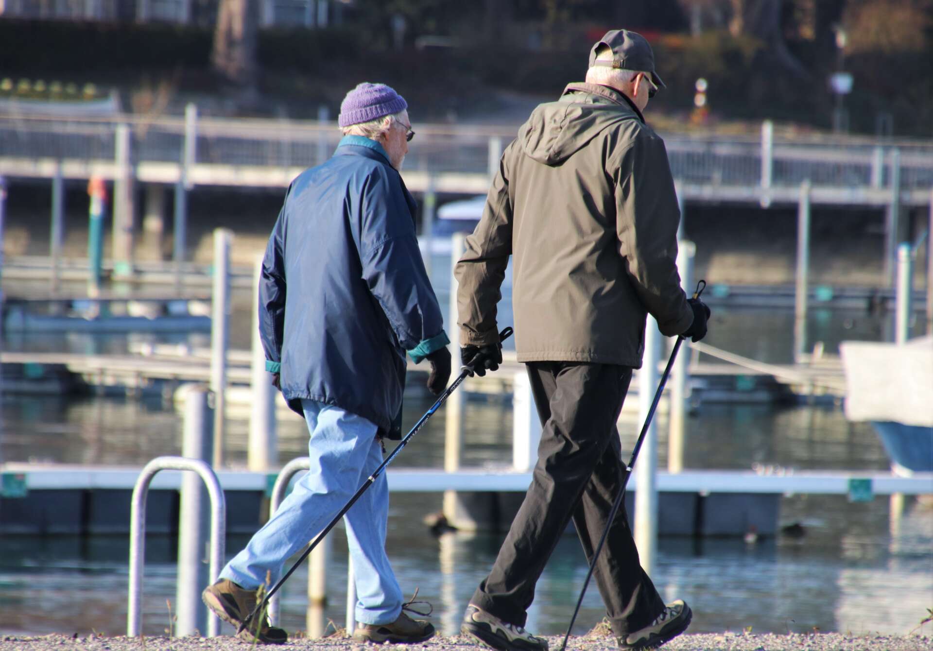 Zwei ältere Menschen beim Nordic Walking an einer Uferpromenade