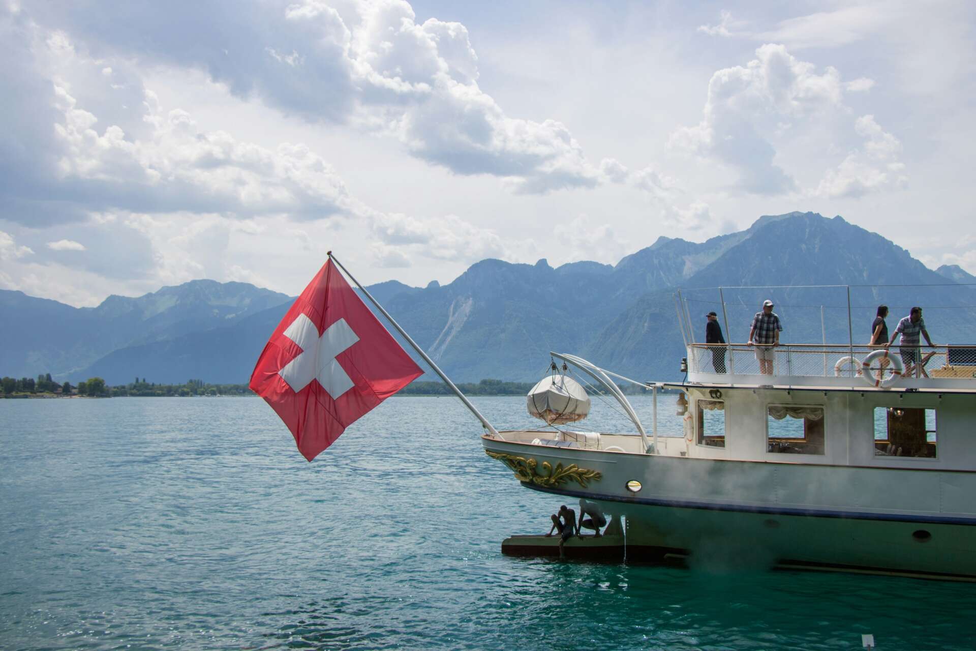 Ausflugsschiff mit Schweizer Flagge auf dem Walensee vor einer beeindruckenden Bergkulisse.