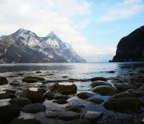 Steiniges Seeufer am Walensee mit Blick auf die umliegenden Berge und das ruhige Wasser.