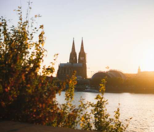Blick über den Rhein auf den Kölner Dom bei Sonnenuntergang.
